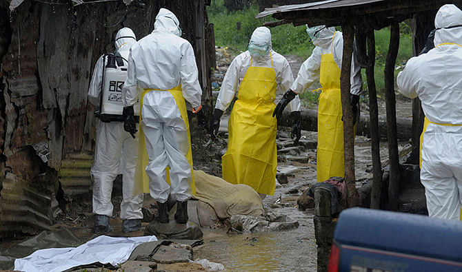 Health workers wearing protective clothing prepare to carry an abandoned dead body presenting with Ebola symptoms at Duwala market in Monrovia. Photo: Reuters 