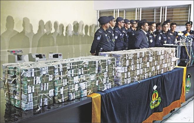 Rab officials hold a press conference yesterday to announce the arrest of the mastermind of Kishoreganj Sonali Bank heist. The recovered money is put on display.   Photo: Star