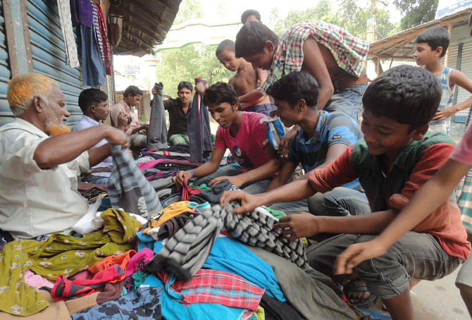 People belonging to low-income group buy second hand warm clothes from roadside vendors at Muktijoddha Chattar (square) area in Lalmonirhat town yesterday as winter is about to set in in the country's northern region . Photo: Star