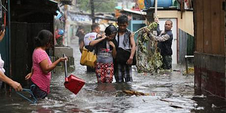 Residents wade through floods as they go back to their home while Typhoon Rammasun batters suburban Quezon city, north of Manila, Philippines July 16. Photo: AP