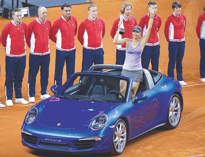 Maria Sharapova holds aloft the Stuttgart Open trophy while standing on the winner's prize, a Porsche 911 Targa sportscar, after the final against Ana Ivanovic yesterday. PHOTO: AFP