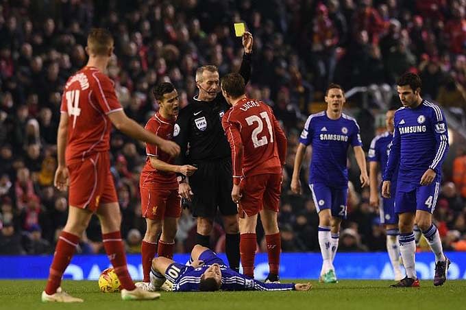 Referee Martin Atkinson shows Liverpool's Lucas Leiva (4th L) a yellow card after a foul on Chelsea's Eden Hazard (floor) during their League Cup match at Anfield on January 20, 2015. Photo: AFP