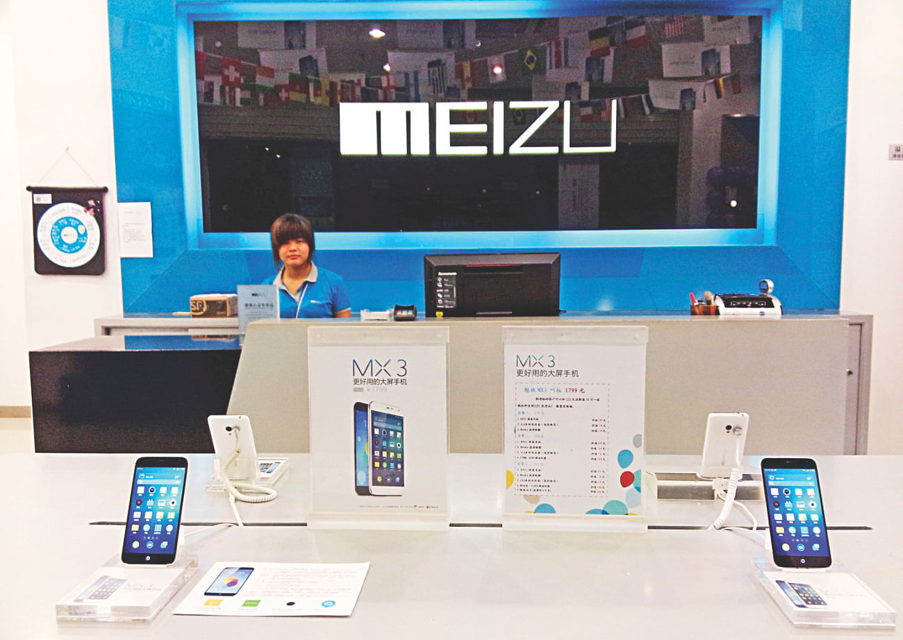 A shop assistant waits for customers at a Meizu store as Meizu MX3 smartphones are seen on display in the foreground, in Shenzhen, Guangdong province. Photo: Reuters/File