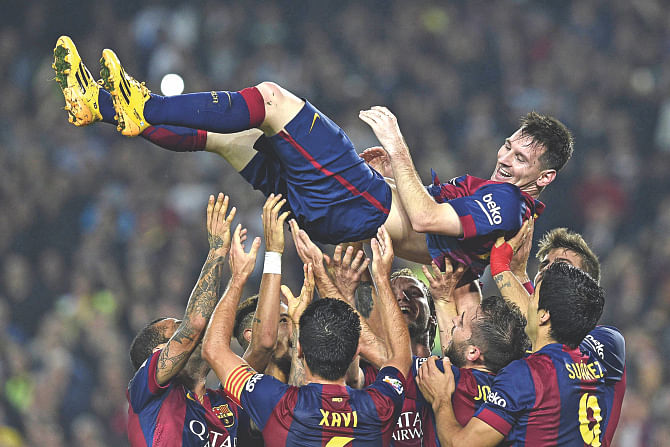 Toast of his teammates, Lionel Messi is lifted into the air as the Barcelona players celebrate his record-breaking feat against Sevilla at Nou Camp on Saturday. PHOTO: afp