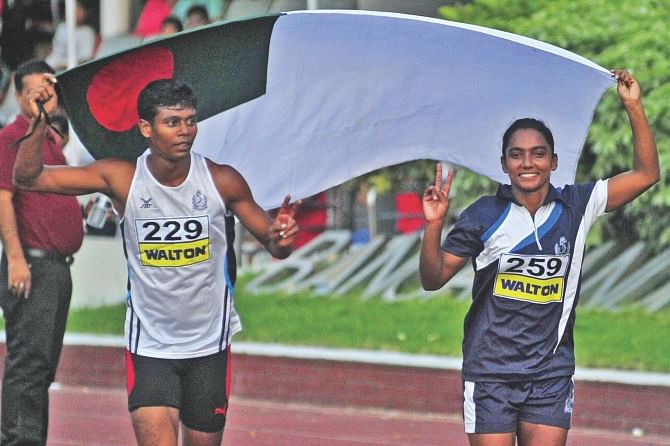 Mezbah Ahmed and Shirin Akter run with the flag of Bangladesh Navy after winning the 100m sprint titles in the Walton 12th Summer Athletics Championships at the Bangabandhu National Stadium yesterday. PHOTO: STAR