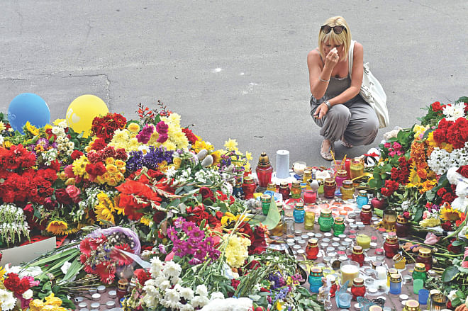 A woman crosses herself as people lay flowers and light candles in front of the Embassy of the Netherlands in Kiev yesterday, to commemorate passengers of Malaysian Airlines flight MH17 which crashed in eastern Ukraine. Photo: AFP