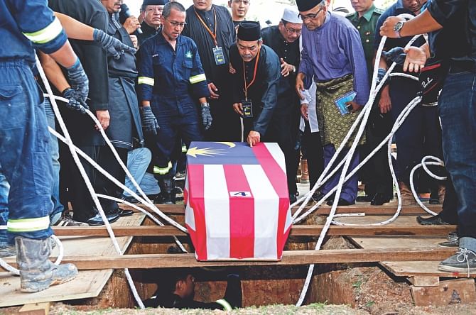 Mohamed Salleh, (C) the father of Malaysia Airlines flight attendant Nur Shazana, one of the Malaysians who perished aboard flight MH17 that was downed in eastern Ukraine, touches her coffin during a burial ceremony in Putrajaya, outside Kuala Lumpur yesterday. Black-clad Malaysians paused for a minute of silence yesterday on a nationwide day of mourning held to sombrely welcome home the first remains of its 43 citizens killed in the MH17 disaster. Photo: AFP