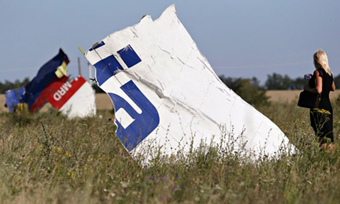 A woman takes a photograph of wreckage at the crash site of Malaysia Airlines flight MH17. Photo: Reuters 