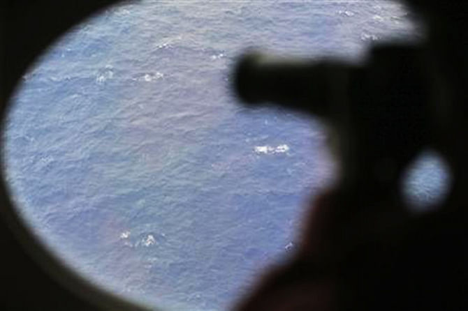 An observer on a Japan Coast Guard Gulfstream aircraft takes photos out of a window while searching for the missing Malaysia Airlines Flight MH370 in Southern Indian Ocean, near Australia, April 1. Photo: AP