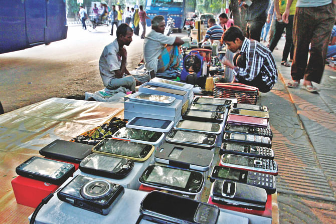 Mobile phones and other electronic goods are displayed at a makeshift market on the footpath opposite the office of Dhaka South City Corporation.  A very wide range of old, new and stolen products are available there at cheaper prices drawing in customers from lower-income groups.  Photo: Anisur Rahman
