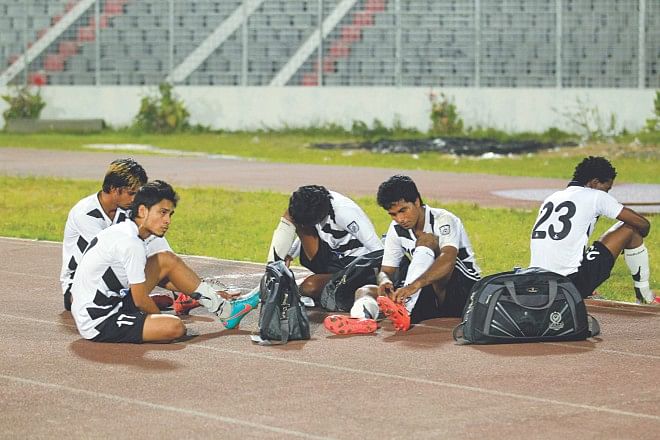 PUSHED TO THE SIDELINES! Dejected Mohammedan players sit on the sidelines of the Bangabandhu National Stadium pitch following their Bangladesh Premier League match against Uttar Baridhara yesterday. PHOTO: STAR