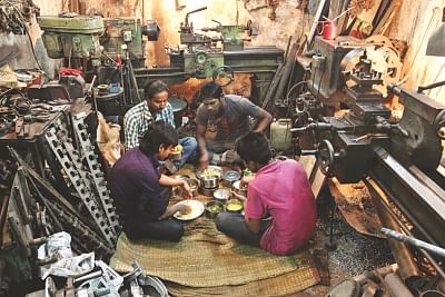 Workers having lunch in a cramped lathe workshop.
