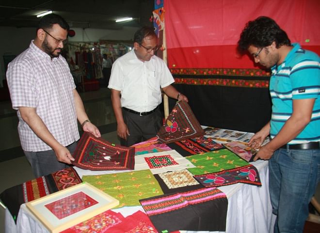 Moinuddin Hasan Rashid, managing director of United Group, and Hasibur Rahman, executive director of Management and Resources Development Initiative (MRDI), take a look at products made by vulnerable women who have developed skills under the CSR initiative of MRDI, in the Unimart Baishakhi fair in the capital. Photo: MRDI