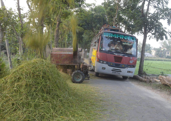 A threshing machine, paddy stalks and straw occupy a portion of Lalmonirhat-Hatibandha road at Boderhat in Hatibandha upazila under Lalmonirhat district, causing hindrance to vehicular movement and posing threat of accidents any time. PHOTO: STAR