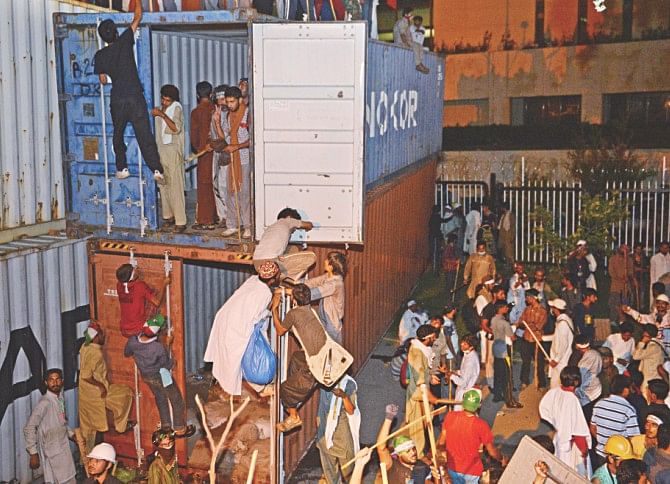 Protesters try to climb containers which were used to block the way of PM's house during the clashes. Photo: AFP