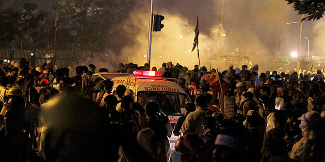  An ambulance carrying injured people makes way through protestors running for cover following police firing tear gas during clashes near prime minister's home in Islamabad, Pakistan, Saturday, August 30. Photo: APAP