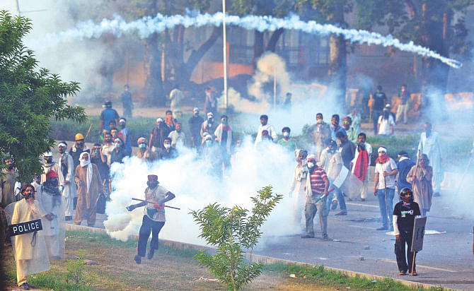 One of the supporters of Canadian cleric Tahir ul Qadri returns a teargas shell towards police during clashes near the Pakistan prime minister's residence in Islamabad yesterday.   Photo: AFP