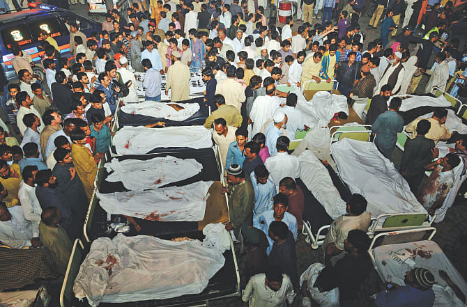 Pakistani relatives gather around the bodies of blast victims after a suicide bomb attack near the Wagah border, yesterday. The blast killed at least 45 people at the main Pakistan-India border crossing.  Photo: AFP
