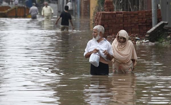 A couple wades through a flooded road after heavy rains in Lahore September 4, 2014. Photo: Reuters