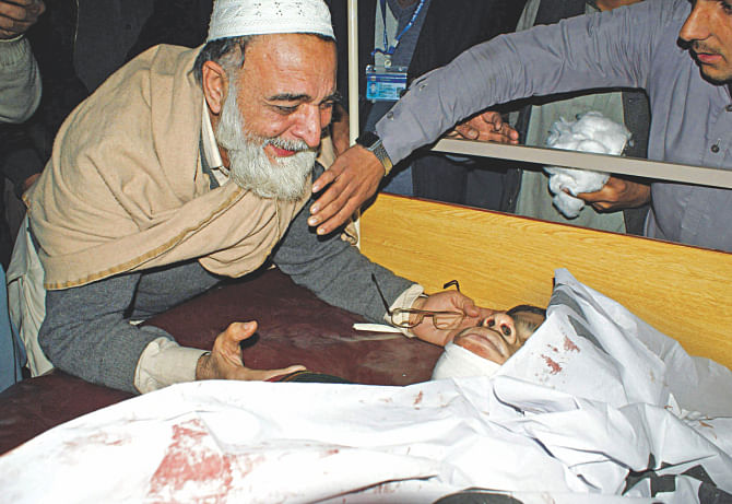 A father mourns beside the body of his son at a hospital after an attack by Taliban gunmen on a school in Peshawar yesterday.  Photo: AFP
