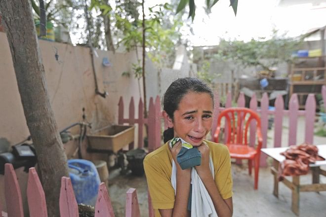 A girl mourns the death of a relative; and medics evacuate an injured man from Shejaiya district, yesterday. Photo: AFP