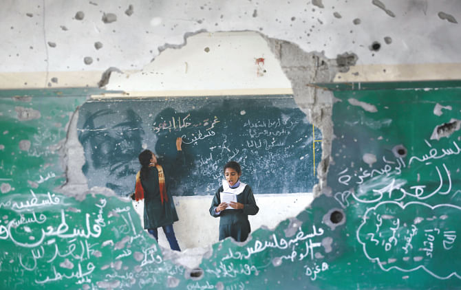 Palestinian girls attend class inside their school which was destroyed during the 50 days of conflict between Israel and Hamas last summer, in the Shejaiya neighborhood of Gaza City, yesterday. Photo: AFP