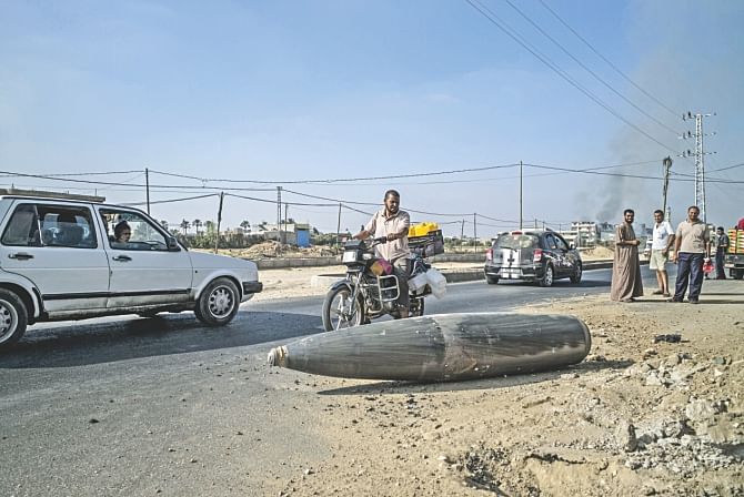 Palestinians look at an unexploded Israeli shell that landed on the main road outside the town of Deir Al-Balah in the central Gaza Strip. Photo: AFP