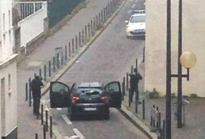 Armed gunmen face police officers near the offices of the French weekly Charlie Hebdo in Paris yesterday, during an attack on the offices of the magazine. Photo: AFP