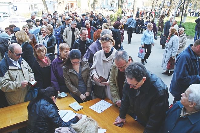 People queue to get their Russian passports in the Crimean capital of Simferopol yesterday. Crimeans have been given a month to expressly state that they want to stay Ukrainian -- or they will automatically become Russian citizens, although they still have to obtain passports. The tumultuous changeover has come in just a month since the ousting of pro-Kremlin president Viktor Yanukovych in Kiev and Russia's capture of Crimea.  Photo:AFP