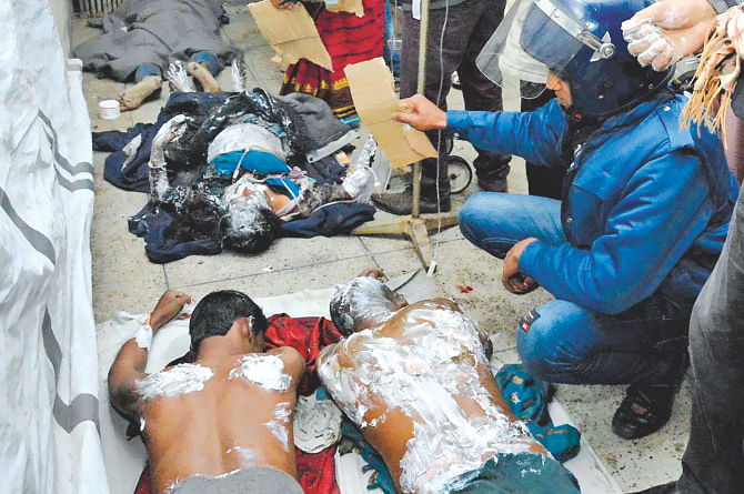 With no room left, the injured in the petrol bomb attack on a bus in Gaibandha being treated on the floor of Rangpur Medical College Hospital yesterday. People are seen fanning them to give them some comfort.  Photo: Star