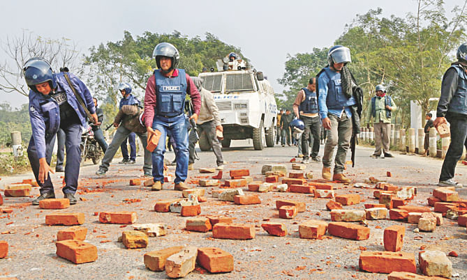 Law enforcers remove bricks and brick chunks from the second bypass of Bogra town in Matidali area after a clash between the police and blockade supporters yesterday. Photo: Star