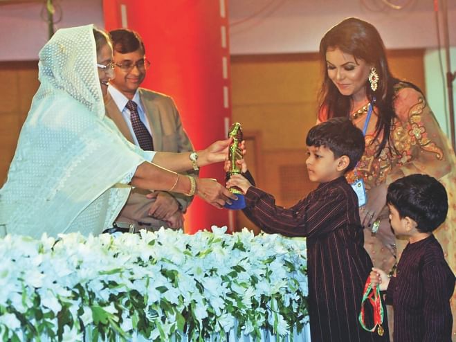 Prime Minister Sheikh Hasina hands over the best director award to the sons of late Humayun Ahmed during the National Film Award 2012 ceremony at the Bangabandhu International Conference Centre yesterday. Photo: BSS