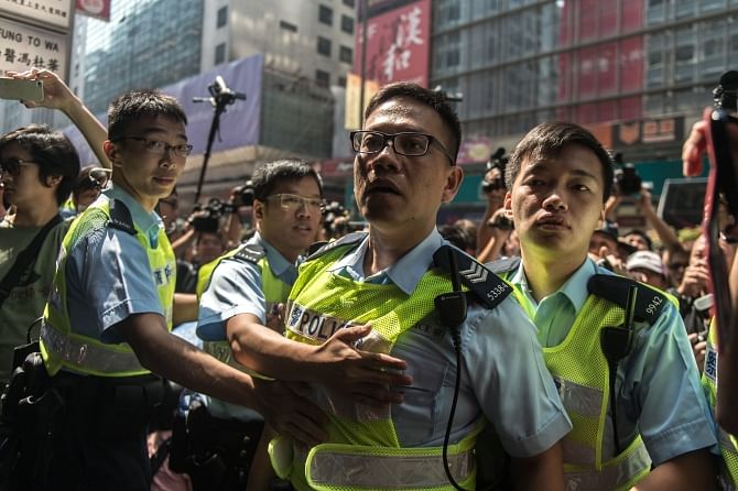 Police restrain a colleague (C) as he reacts to being shouted at by a member of the Occupy movement in the district yesterday.  Photo: AFP