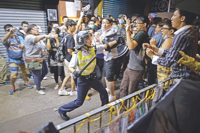 A policeman holding a baton advances towards pro-democracy protesters as they clash on a street in the Mong Kok district of Hong Kong early yesterday. Hong Kong's embattled government said it will open talks with student demonstrators tomorrow, after three nights of violent clashes between police and protesters who have paralysed parts of the city with mass pro-democracy rallies. Photo: AFP