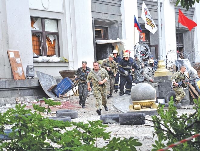 Pro-Russian militants and firemen run away as they leave the Regional State building they seized during a shoot-out with Ukrainian border guards defending the Federal Border Headquarters building in the eastern Ukrainian city of Lugansk yesterday.  Photo: AFP