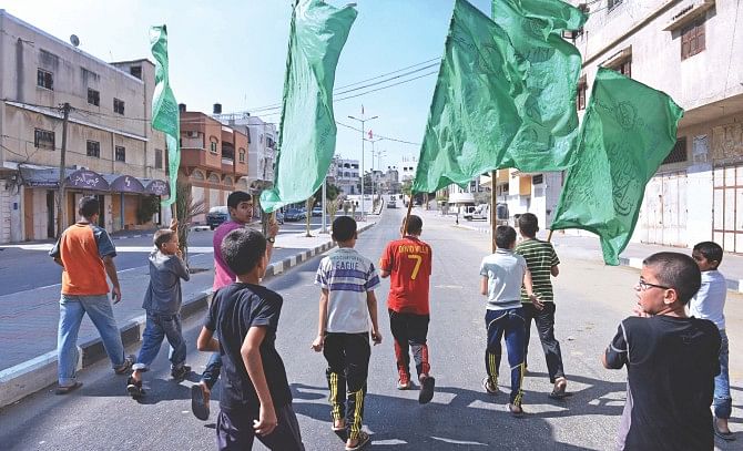 Palestinian boys carry Hamas flags as they lead a funeral procession yesterday in Jabalia of a man who was killed after being targeted by an Israeli airstrike late Sunday -- hours before a ceasefire between Israel and Hamas was scheduled to begin. A fresh 72-hour ceasefire between Israel and Hamas came into effect in Gaza yesterday, paving the way for talks in Egypt aimed at a durable end to a month-long conflict that has wreaked devastating bloodshed. Photo: AFP