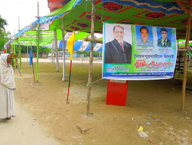 ALL FOR PUBLIC DEMAND?..... This newly set up Eidgah, made after unauthorised filling up of Jorapukur, a water body owned by Bangladesh Railway at Saidpur municipality, holds a large canopy and a digital banner displaying Eid greetings from local lawmaker Shawkat Chowdhury who inaugurated the filling work on June 14. The photo was taken on Wednesday, the day after the Eid-ul-Fitr. PHOTO: STAR