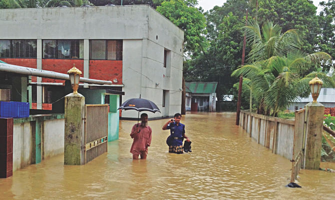 Phulgazi Police Station in Feni is flooded with waist-deep water rushing through breaches on an embankment. Photo: Star