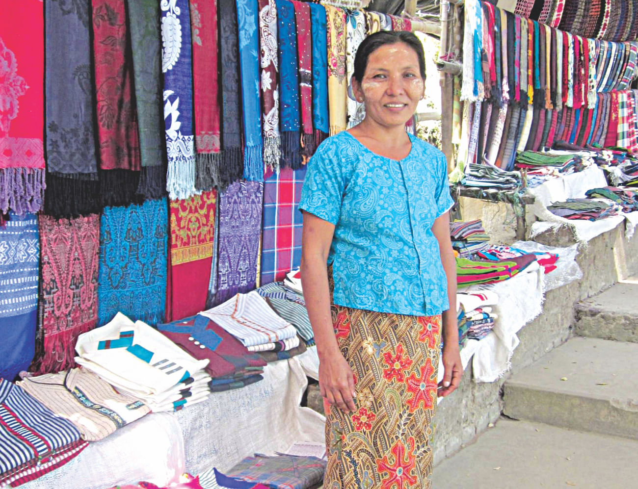 Rakhine woman Liri sells a variety of clothes, including some woven by herself, at her makeshift shop on the steps leading to Adinath temple in Moheshkhali Island under Cox's Bazar district. She, along with other small traders in the area, now sees scanty income as her potential buyers, mostly the visitors and pilgrims to the famous temple, are much less than usual due to the countrywide non-stop transport embargo enforced by BNP-led 20-party alliance since January 6.   PHOTO: STAR