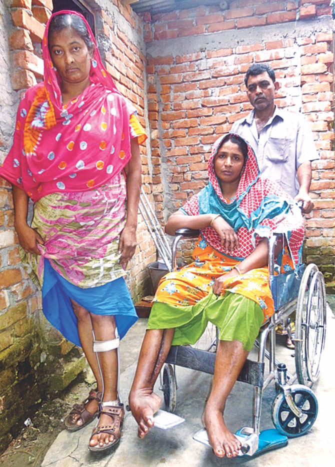 Feli Begum, standing left, and Nilufa Begum, in the wheelchair, two survivors of the Rana Plaza collapse last year, who are in dire need of proper treatment. They are yet to receive any compensation, which will enable them to avail medical care and thus save their lives. The photo was taken in front of their houses at Rajashon, Savar on Sunday. Photo: rashad ahamad