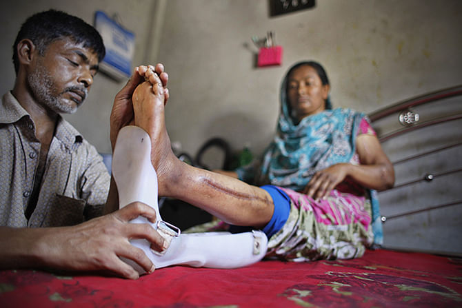 Hasu attaches an ankle-foot orthosis to the left leg of his wife Feli, one of the workers pulled out alive from the rubble of Rana Plaza last year. Photo: Star