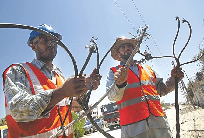 Palestinian electricity company workers inspect power lines destroyed by Israeli attacks. Photo: AFP