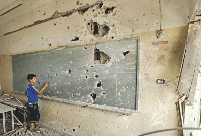 A Palestinian boy writes on a shrapnel riddled backboard at a school in Gaza City yesterday. Photo: AFP