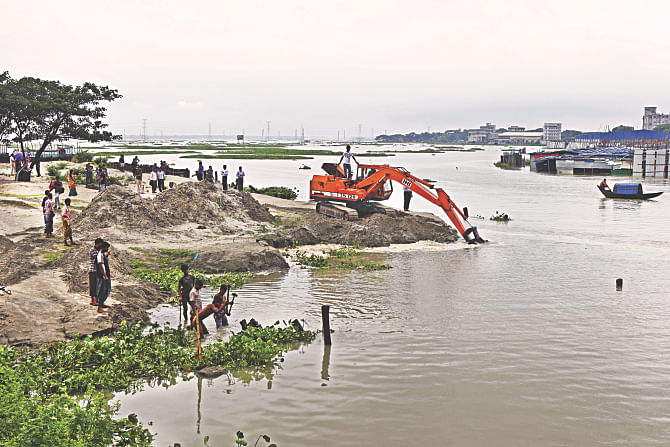 The BIWTA yesterday removes the soil a grabber had dumped in the Turag at Dhour near Ashulia to occupy the river. Photo: Rashed Shumon
