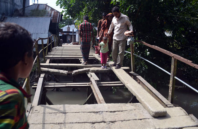People take a risky walk on this awfully dilapidated bridge to cross Bogi canal in Kalaiya union of Baufal upazila under Patuakhali district, thanks to the callousness of the authorities who did not bother to repair the structure for years.  PHOTO: STAR