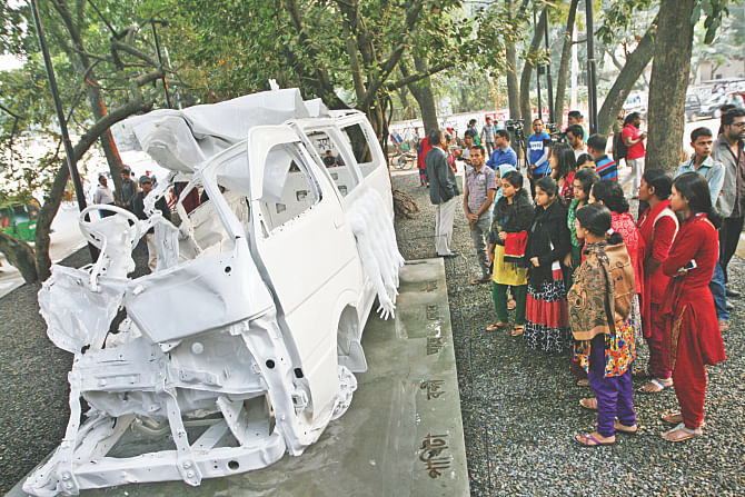 Visitors look at the Road Accident Memorial Installation after it opened to the public at a traffic island near Dhaka University's Shamsunnahar Hall yesterday. The installation comprises the wreckage of a microbus, which got into a road crash on Dhaka-Aricha highway in Manikganj on August 13, 2011 leading to the death of noted filmmaker Tareque Masud and media personality Mishuk Munier.  Photo: Palash Khan