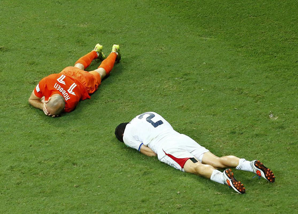 Arjen Robben of the Netherlands and Costa Rica's Johnny Acosta lie on the pitch after colliding with each other during extra time in their 2014 World Cup quarter-finals at the Fonte Nova arena in Salvador July 5, 2014. Acosta was shown yellow card for the action.