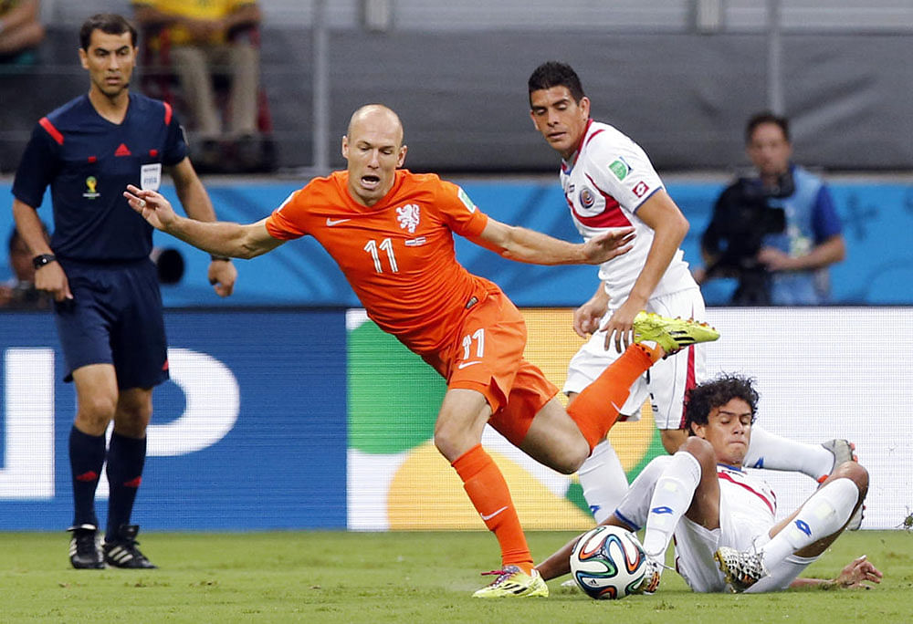 Referee Ravshan Irmatov from Uzbekistan watches as Netherlands' Arjen Robben stubbles over Costa Rica's Yeltsin Tejeda during the World Cup quarterfinal soccer match at the Arena Fonte Nova in Salvador, Brazil, Saturday, July 5, 2014.