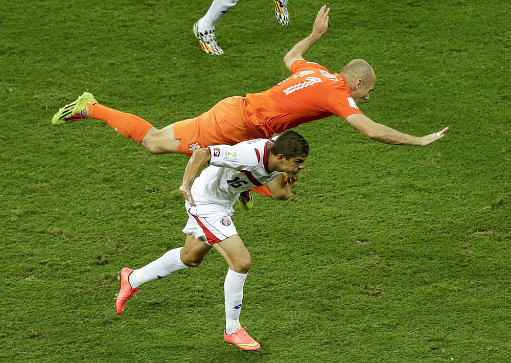 Netherlands' Arjen Robben, top, falls over Costa Rica's Cristian Gamboa during the World Cup quarterfinal soccer match between the Netherlands and Costa Rica at the Arena Fonte Nova in Salvador, Brazil, Saturday, July 5, 2014.