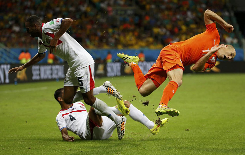 Arjen Robben of the Netherlands (R) falls after a challenge by Costa Rica's Celso Borges (5) and Michael Umana during their 2014 World Cup quarter-finals at the Fonte Nova arena in Salvador July 5, 2014.